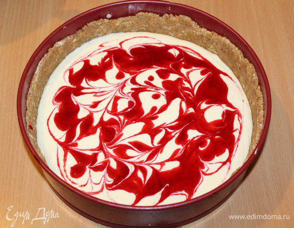 Разогрейте духовку до 180°C. Половину творожной массы выложите в форму, распределив поверх коржа. Треть ягодного сока и вылейте сверху, а затем, проводя по творожной массе деревянной шпажкой, сделайте в ней разводы.