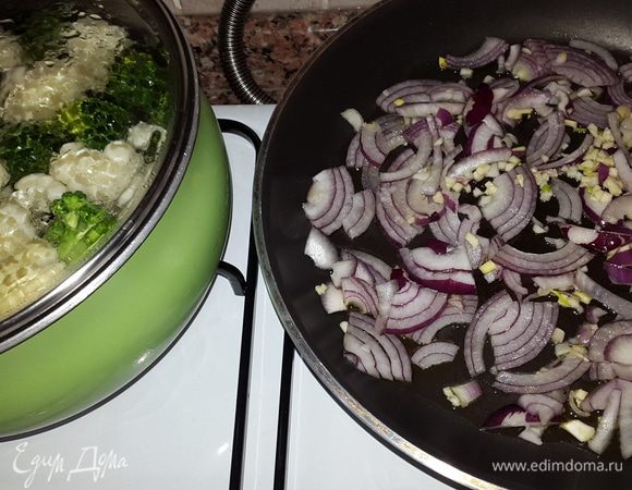 Брокколи и цветную капусту моем, разбираем на соцветия и бланшируем в подсоленой воде 7 минут. 
Красный лук режем на четверть кольца, чеснок мелко рубим и обжариваем вместе на оливковом масле до мягкости.