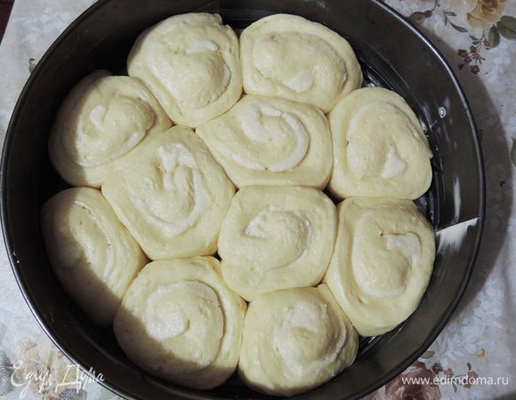 Оставить форму в теплом месте примерно на час (до тех пор, пока рулетики настолько увеличатся в объеме, что заполнят всю форму). Пока пирог расстаивается, приготовить сладкое молоко. Для этого молоко нагреть вместе с сахаром. Помешивая, дождаться полного растворения сахара и остудить до комнатной температуры.
