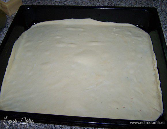 Тесто раскатываем очень тонко, так, чтобы можно было им укрыть противень. Смазываем тесто соусом, не доходя до краёв по 3-4 см.