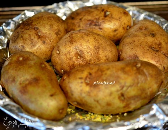 Картофель крупный промыть (если небольшой, то можно добавить клубней), обмакнуть бумажным полотенцем, вилкой проткнуть. Выложить на приготовленный противень с солью и пряностями. Смазать с оливковым маслом. Поставить в духовку на 60-75 мин.