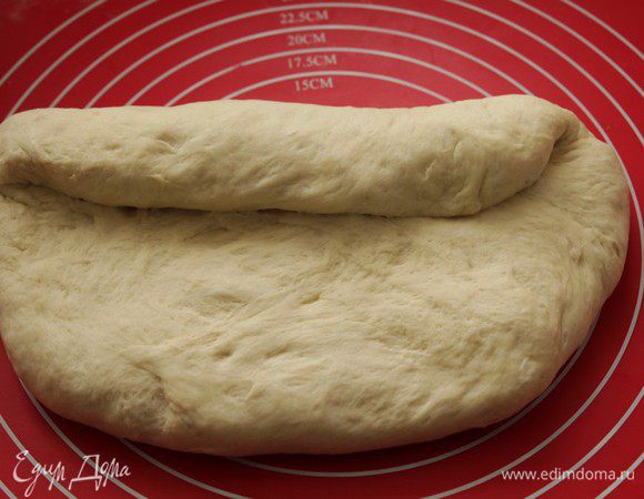 Далее кладем тесто на стол швом вверх (куда загибали концы), расплющиваем и загибаем один край.