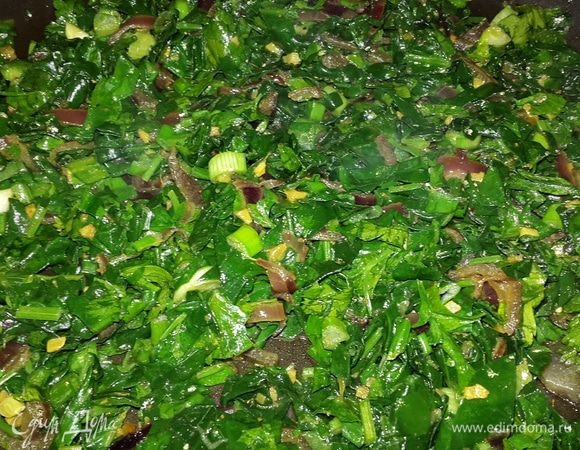 Отправляем к луку сначала шпинат, перемешиваем и тушим до мягкости. Затем добавляем зелень, солим, перчим, перемешиваем, прогреваем пару минут и снимаем с огня.

Выкладываем готовый шпинат в кастрюльку, накрываем крышкой и отставляем в сторону.