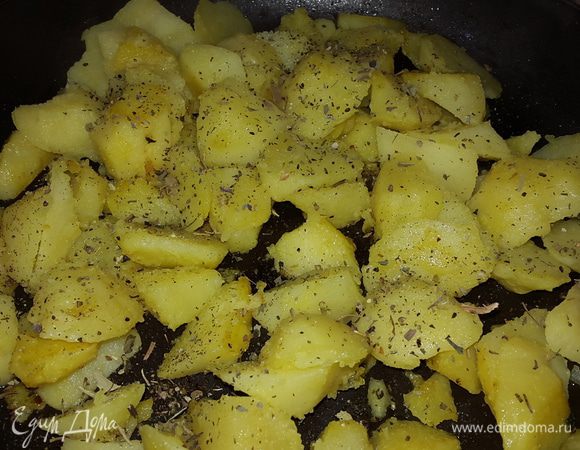 Когда картофель поджарится, немного солим, посыпаем сушеным базиликом, перемешиваем.