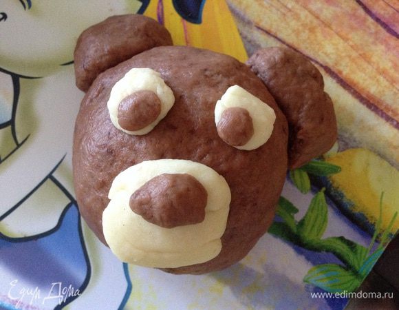 Разделить тесто на 6 равных частей, из каждой части сформировать голову, в центр которой положить кусочек шоколада. Приделать ушки, мордочку и глазки (места крепления смазать молоком или яйцом).