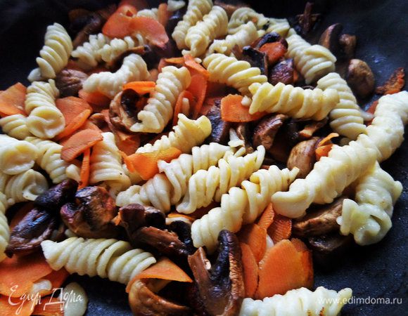 Затем к ним высыпаем фузилли, прогреем немного вместе на огне.