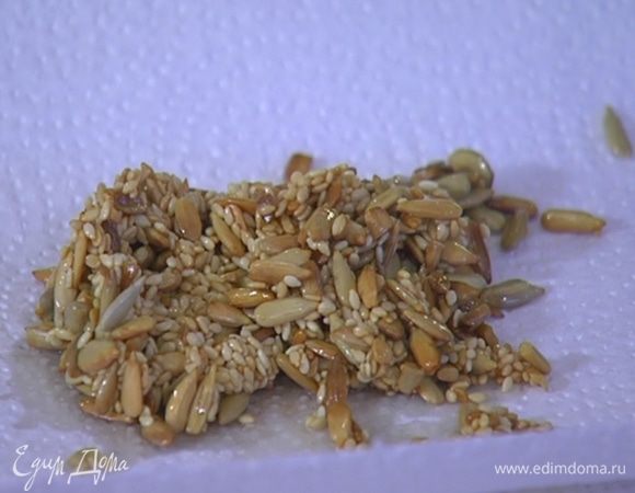 Разогреть в сковороде растительное масло, всыпать семечки, посолить, затем добавить кунжут и обжарить все до золотистого цвета. Выложить семена на бумажное полотенце, чтобы удалить излишки масла.