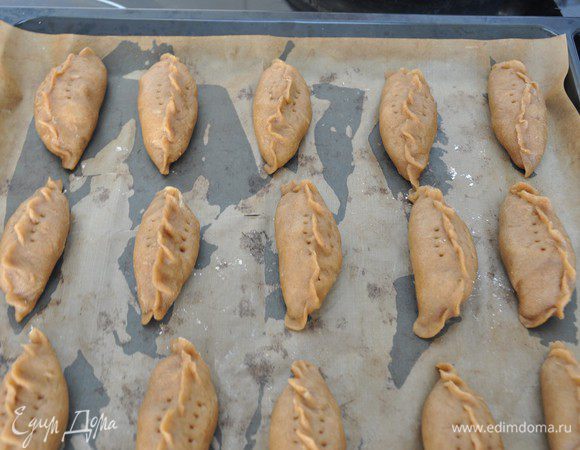 Края хорошо защипнуть. Переложить пирожки на застеленный пергаментом противень, наколоть тесто вилкой для выхода пара и выпекать около 30 минут при температуре 180 градусов.