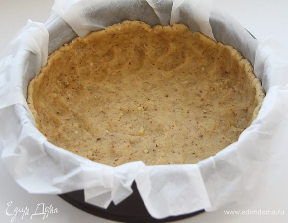 Разъёмную форму диаметром 20 см застелить бумагой для выпечки, распределить тесто по дну и бортикам. Убрать в морозилку на 20 минут.