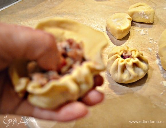 Кладем кружок на ладонь левой руки и правой начинаем защипывать края по кругу (указательным пальцем левой руки в это время углубляем фарш вовнутрь), обязательно оставляя отверстие, через которое будет выходить пар.
