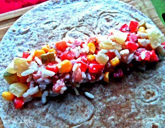 Половину начинки распределяем в центре тортильи, сворачиваем в рулетик, концы желательно подвернуть.