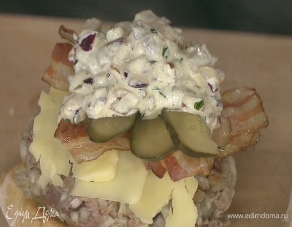 Один кусок хлеба смазать дижонским соусом, выложить на него котлету, сыр, бекон, полоски огурца, смазать все соусом и накрыть вторым куском хлеба.