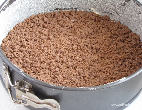 Разъемную форму диаметром 20 см смазать сливочным маслом и обсыпать манкой. Достать тесто из морозилки, одну часть натереть на крупной терке и распределить по форме.