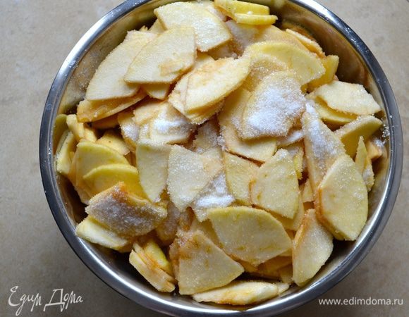 Яблоки подготовить заранее, за 1-2 часа до того, как Вы соберитесь печь пирог. Итак, яблоки лучше взять сорта ренет (или зеленые, типа Симиренко). Вымыть, очистить яблоки и нарезать на тонкие дольки толщиной примерно 2 мм. Выложить яблоки в миску и пересыпать сахаром. Осторожно перемешать, чтобы яблоки не поломались!