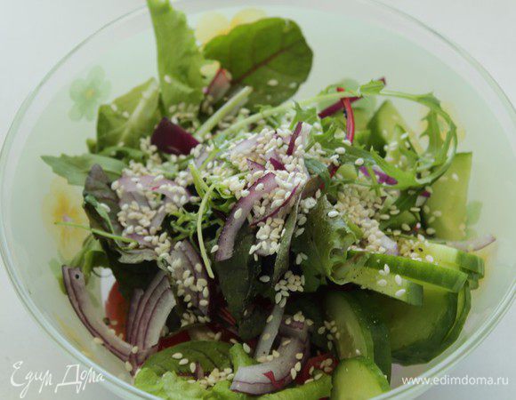 Добавить в салат вяленые помидоры, посыпать кунжутом, перемешать.