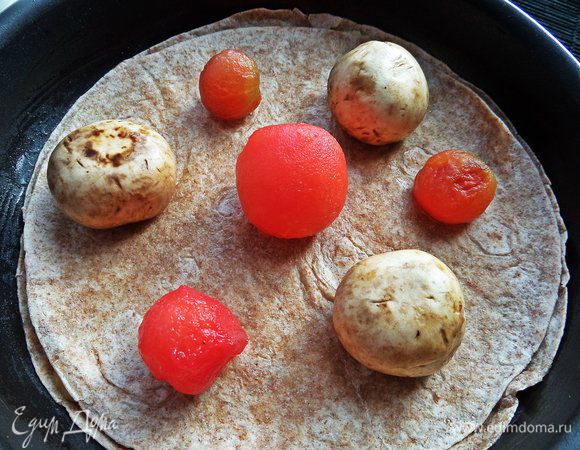 Но мы идём дальше! Накрываем второй тортильей и раскладываем мелкие томаты (можно крупные дольками) без кожицы и грибы.