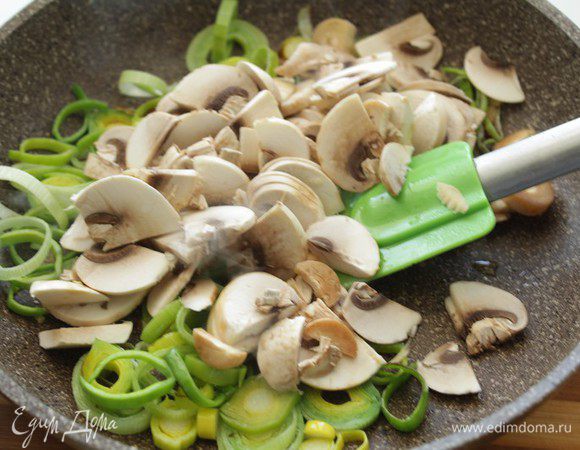 В сковороде разогреть оливковое масло, выложить порезанный кольцами лук и слегка обжарить. Добавить нарезанные шампиньоны, немного потушить.