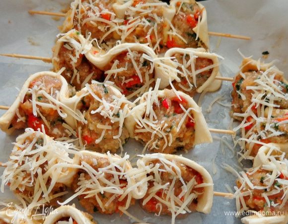 На деревянные шпажки наколоть тесто и слепленные мясные шарики. При желании посыпать их тертым сыром. Запекать в духовке при 200 градусах около 45 минут.