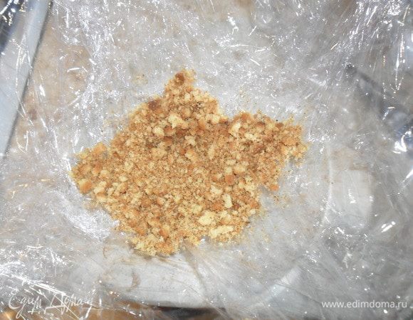 Круглую форму (салатник) застелить пленкой и на дно всыпать немного крошки.