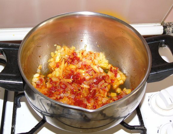 Когда лук начнет зарумяниваться, добавить 1 ст. л. с горкой хорошей томатной пасты. Если в качестве ее вы сомневаетесь или смущает ее изначальный вкус (например, кислый), замените ее тремя спелыми помидорами. Обжарить пасту или помидоры пару минут с луком. 