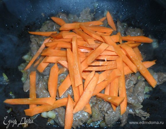 К обжаренному мясу с луком добавить крупно нарезанную морковь. Обжарить несколько минут.