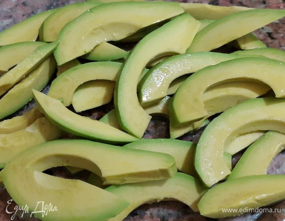 Авокадо моем, чистим, удаляем косточку, режем ломтиками толщиной примерно 0,7 см и сбрызгиваем соком половины лимона.