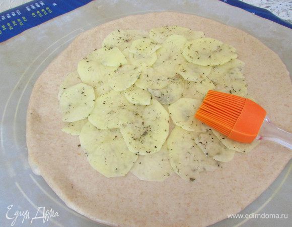 Тесто вынуть из холодильника. Разделить на две равные части (получилось 2 галеты). Тесто раскатать в круг. Выложить в один слой ломтики картошки, не доходя до края. Смазать растительным маслом, посыпать солью, перчиком и прованскими травами.