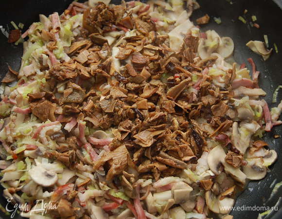 Воду, в которой замачивались грибы процедить через сито и марлю. Этот грибной бульон понадобится нам! Грибы произвольно нарезать и добавить в сковороду. Обжаривать еще 3-4 минуты на тихом огне.