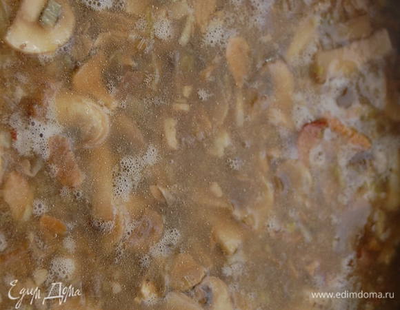 Перекладываем содержимое сковороды в кастрюлю, вливаем белое вино, грибную воду и куриный бульон. Довести до кипения и проварить 15 минут на тихом огне. Добавить рис, и варить еще 10 минут.