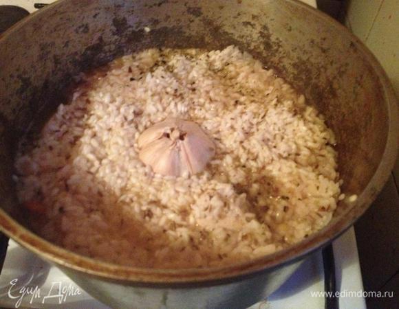 Заложить рис. Добавить специи. В середину положить целую головку чеснока.
Когда вода выкипит до уровня риса, то уменьшить огонь и закрыть крышкой.
По мере выкипания воды осторожно лопаткой собирать рис к середине. Не перемешивать.
Когда воды в сотейнике не останется, выключить огонь и закрыть сотейник крышкой. Дать постоять минут десять.