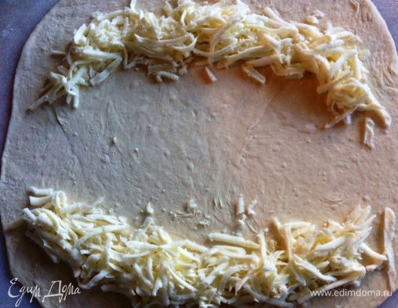 Из одной части раскатываем корж толщиной 0,5 мм, по бокам как на фото выкладываем сулугуни.