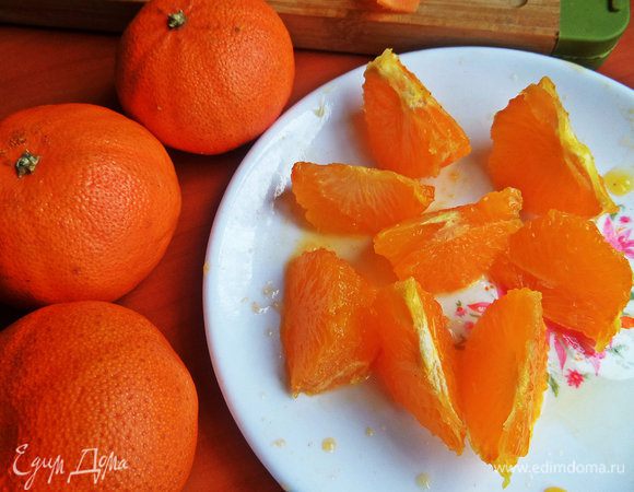 С мандарина срезать ножом вначале кожицу на манер яблока, а потом нарезать на сегменты, чтобы вся белая мякоть осталась на шкурке. Разрезаем пополам каждую дольку.