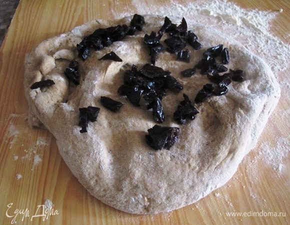 Готовое тесто обминаем, слегка распластываем руками по доске припыленной мукой, сверху насыпаем нарезанный чернослив, скатываем рулетом, затем формируем комок и кладем на противень в расстоечной корзине или прямо так. Включаем духовку на 50 градусов и оставляем тесто для подъема на 20-30 минут.
Затем включаем духовку на 180 градусов и выпекаем 40-45 минут, периодически спрыскивая его поверхность водой из пульверизатора, раза три-четыре за время выпечки. Это заменяет пар в духовке.