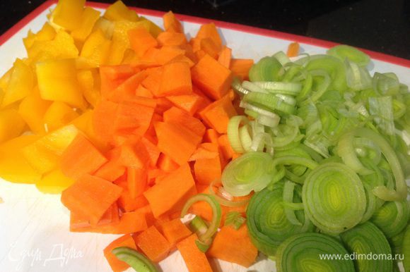 Морковь очистите, у перца удалите семена, порежьте небольшими квадратиками. Лук-порей нарежьте кольцами.