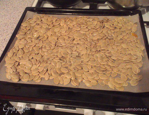 Дальше на противень выкладываем пергамент и на него семечки. Распределяем семечки ровным слоем по всей поверхности пергамента. И готовим их так минут 20-25, периодически их помешивая для полного удаления влаги из всех слоев.