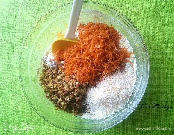 Добавляем в смесь просеянную муку, разрыхлитель, соду, ванильный сахар, гвоздику, кардамон, соль и перемешиваем. 
Дальше вмешиваем морковь, орехи и кокосовую стружку.