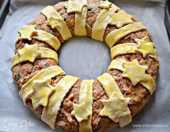 На присыпанной мукой поверхности раскатайте тесто в тонкий пласт и нарежьте его на полоски шириной 2-2,5 см (длина полосок должна соответствовать толщине кольца). Уложите полоски на кольцо на одинаковом расстоянии друг от друга. Из оставшегося теста сформируйте украшение и уложите сверху на полоски. Взбейте оставшиеся желтки и смажьте ими полоски и украшения из теста. Духовку разогрейте до 180г и выпекайте мясное кольцо около 45 минут. Если тесто начнёт подгорать, накройте мясное кольцо фольгой.