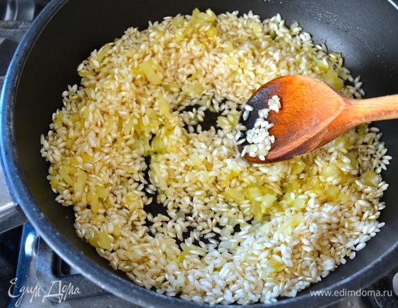 Минут через 5 всыпать в сковороду сухой рис, не промывая его предварительно водой. Перемешать и позволить рису в течение одной минуты пропитаться ароматами и смешаться с луком. Через минуту увеличить огонь и влить белое сухое вино. Дать ему выпариться.