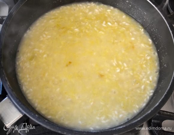 Далее добавить горячий бульон. Около двух половников, так, чтобы слой жидкости покрывал рис, как на фото. Огонь уменьшить до среднего. Готовить ризотто, подливая горячий бульон по мере того, как он будет впитываться, и время от времени перемешивая. Варить 13 минут.