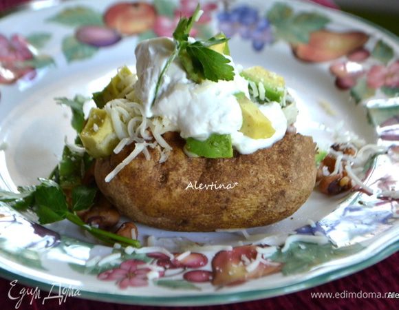 Авокадо очистим от кожуры и ядра, порежем на кубики. Сыр натереть на терке. Зелень порубить. Готовый картофель разрезать на 2 части книжкой. Выложить готовую пряную начинку из фасоли, добавить авокадо, сметану, посыпать сыром, зелень.