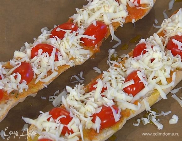 Помидоры черри разрезать пополам и выложить на половинки багета срезами вниз, посыпать натертым сыром и сбрызнуть оставшимся оливковым маслом Extra Virgin.