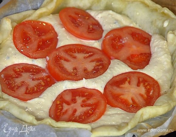 На подпеченный корж равномерно выложить творожную начинку, сверху разложить кружки помидора и немного вдавить их в творог.