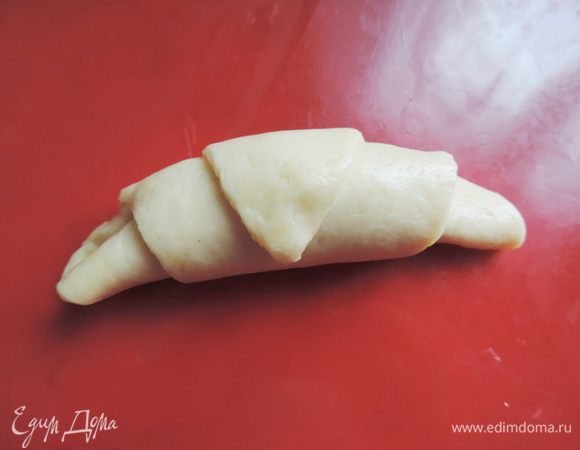 Теперь скатываем тесто рулетиком от широкого края к узкому. "Хвостик" старайтесь прятать под рогалик иначе во время выпечки он поднимется и будет торчать)