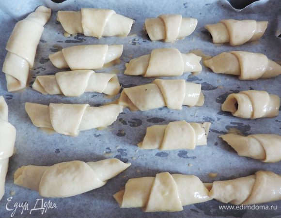 Готовые рогалики выкладываем на противень с пергаментом, смазываем их слегка взбитым яйцом. Расстойки давать не нужно, подготовили противень - выпекаем.