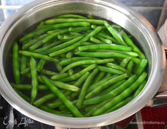 Первым делом подготовить овощи, которые должны пройти термическую обработку. Зеленую стручковую фасоль вымыть и обрезать "хвостики" по краям. Выложить подготовленные таким образом стручки фасоли в кипящую воду. Проварить 3-4 минуты.  