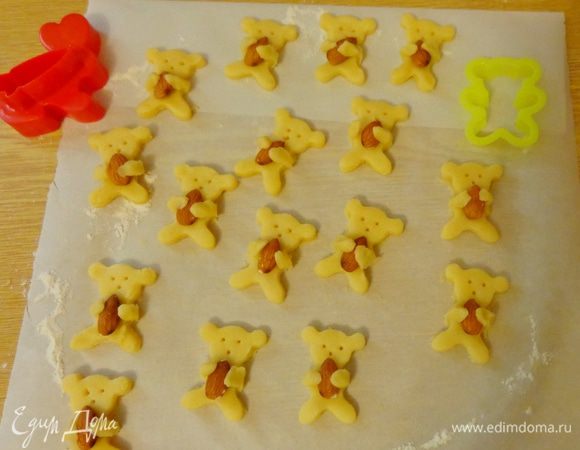 Раскатать тесто до толщины 5 мм, охладить и вырезать мишек. Вложить им в лапки миндаль. Иголочкой наметить глазки и носики.