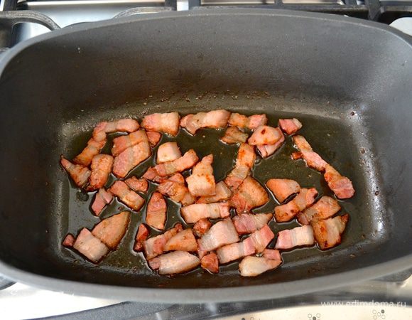 В глубокой кастрюле (казанке) с тяжелым дном, которую можно затем поставить в духовку, разогреть оливковое масло и обжарить сначала бекон до золотистого цвета.