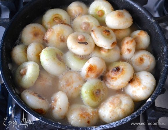 В этот момент добавить к луку бульон и гвоздику. Накрыть крышкой и готовить на слабом огне, пока луковички не станут мягкими и соус не уменьшится в объеме! Если потребуется, в процессе можно добавить еще немного бульона.