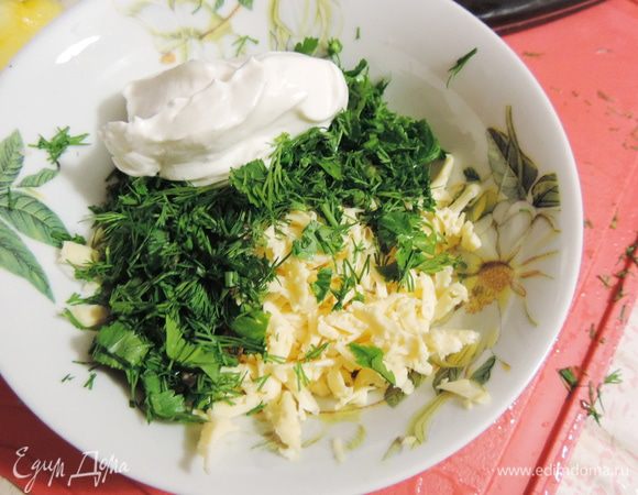 Пока рыбка маринуется, приготовим начинку. Измельчаем зелень (я люблю побольше, а вы ориентируйтесь на свой вкус), сыр натираем на крупной терке. Добавляем ложку сметаны и перемешиваем.