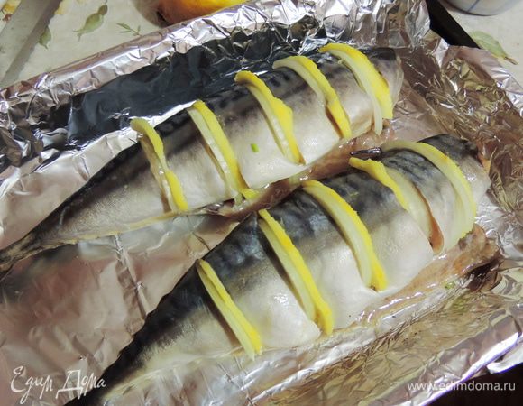 Затем нарезаем рыбку на порционные кусочки, не прорезая полностью. В полученные надрезы вкладываем тоненькие полукольца лука и лимона.